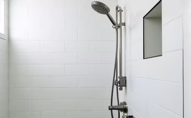 A modern bathroom showcasing a newly updated set of fixtures, including a stainless steel faucet, a sleek rain showerhead, and an energy-efficient light fixture, all against a backdrop of clean, white tiles